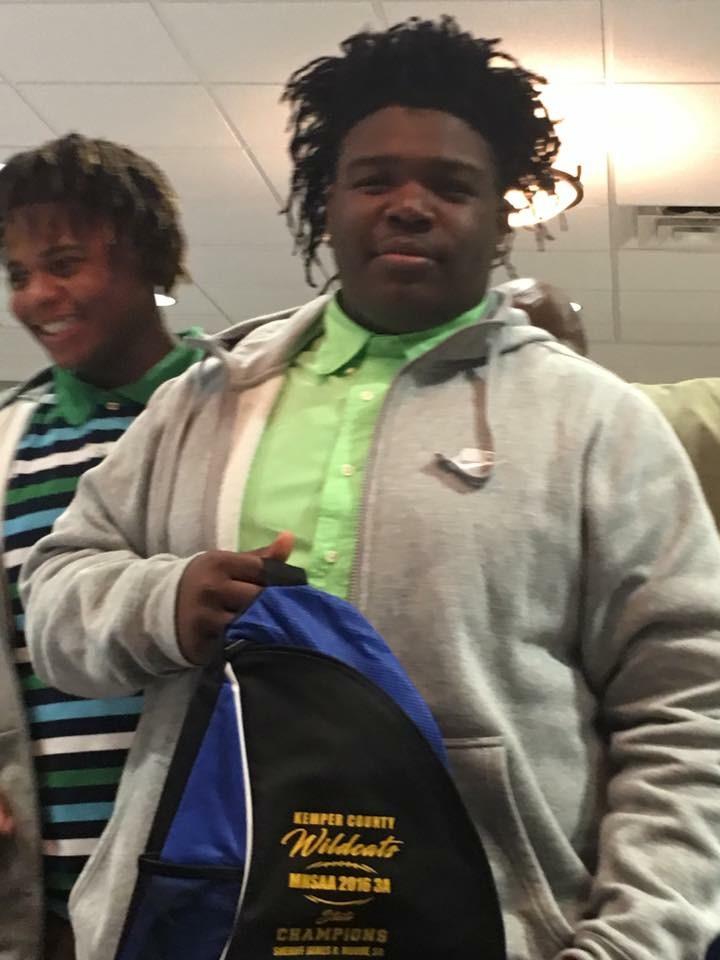 Young man holding Kemper County Wildcats backpack